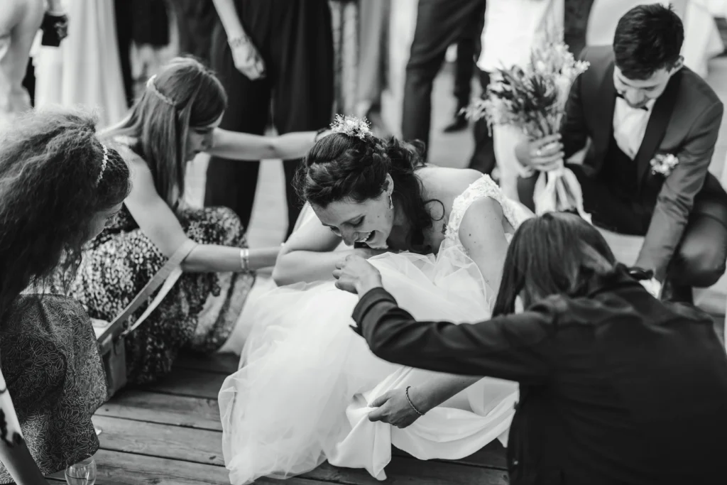 Mariée qui essaye de remettre sa robe de mariée avec l'aide de son mari et de ses invités