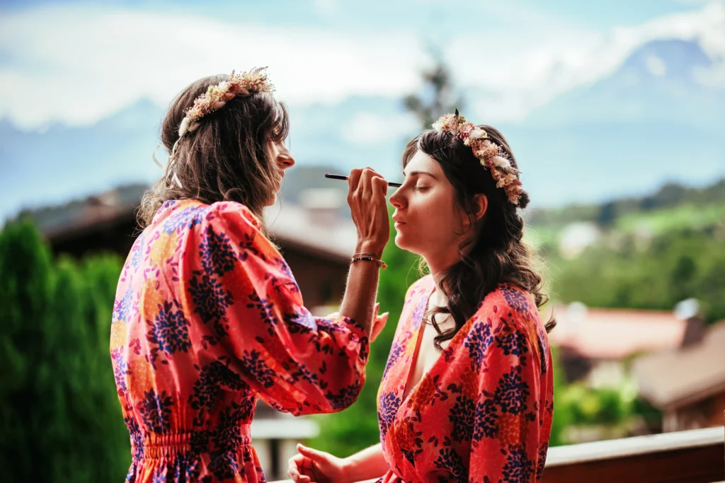 Maquillage mutuel des témoins de mariage sur le balcon avec vue sur les montagnes