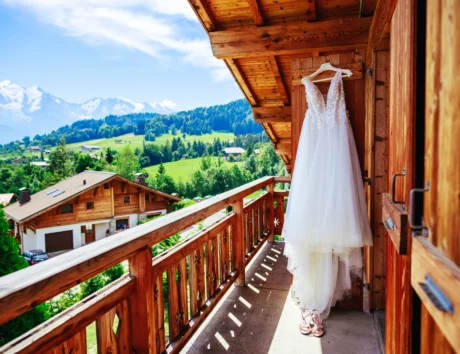 Photo de la robe de mariée et des chaussures de la mariée, photographié sur le balcon d'un chalet avec vue sur les montagnes alentours