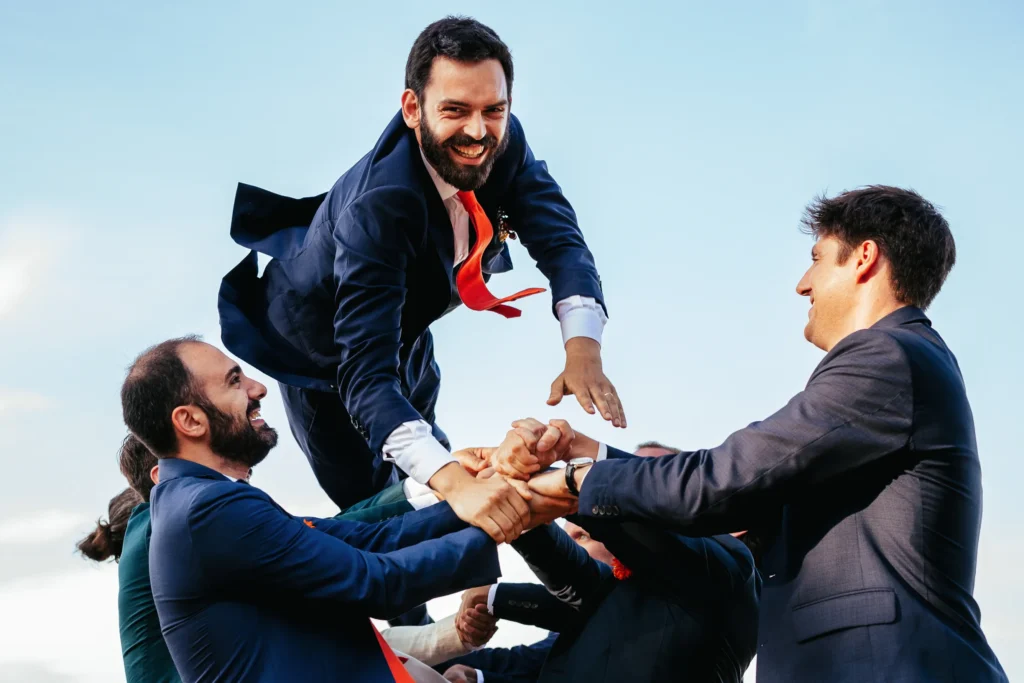 photo de groupe originale où le marié est lancé dans les airs